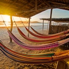 176616416
Hammock; Horizontal; Colombia; La Guajira; Travel Destinations; Idyllic; Blue; Water; Columbia; Coastline; Outdoors; Yellow; Sun; Sand; Multi Colored; Sea; Tropical Climate; Beach; Photography; Scenics - Nature; Sunset; Relaxation; No People; Cabo de la Vela; Orange; Sky; Orange Color;
Hammocks on a beach at sunset.