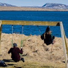 Children on swings on the shore of Videy island in Iceland.